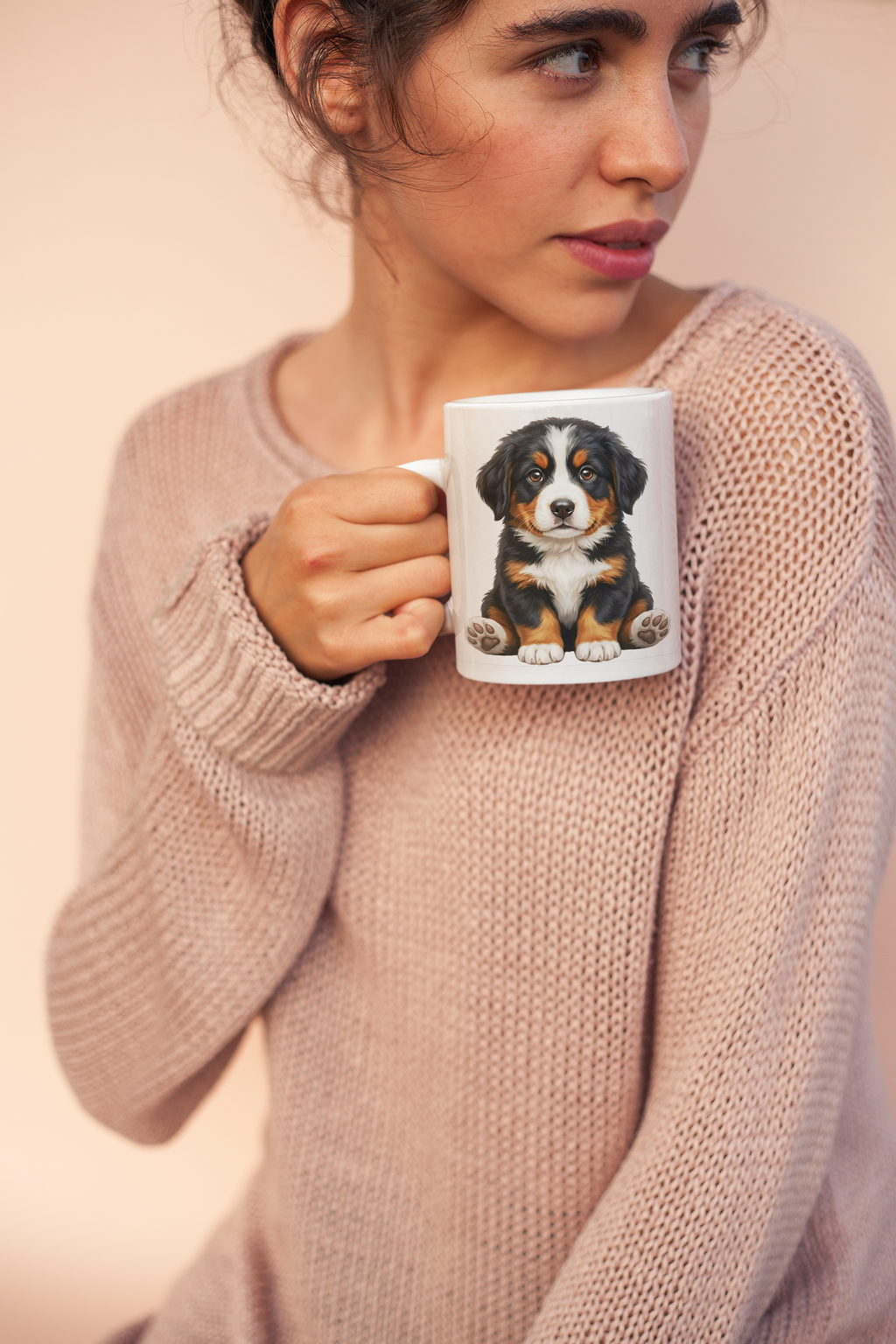 A person smiling while holding a white ceramic mug featuring a fluffy Bernese Mountain Dog puppy design to show the 11oz scale.